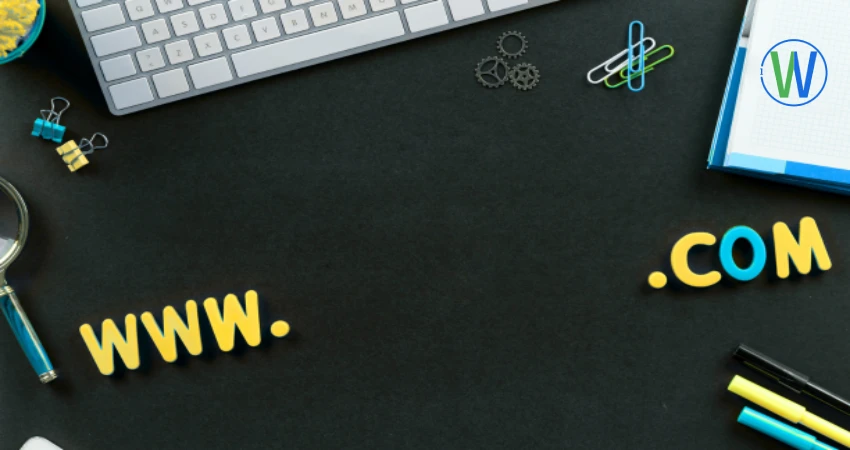 A black desk features a keyboard and the words "www .com" in colorful letters. A WordPress logo sits on a white pad, adding a touch of design flair.
