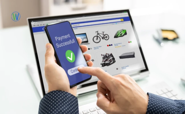 يُجري شخص معاملةً عبر الإنترنت. يعرض الكمبيوتر المحمول موقعًا للتسوق الإلكتروني، بينما يؤكد الهاتف "نجاح الدفع".