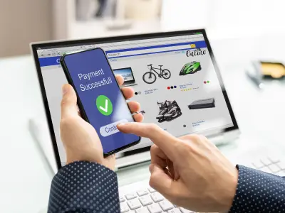 شخص يستخدم هاتفه للدفع مقابل التسوق عبر الإنترنت. يظهر على الهاتف عبارة "تم الدفع بنجاح!" ويتم استخدامه للنقر على "متابعة".