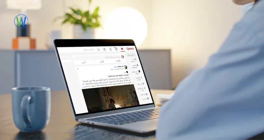 شخص يستخدم جهاز كمبيوتر محمولًا على مكتب بجوار كوب. تعرض شاشة الكمبيوتر المحمول صفحة 
Quora. النص المكتوب على الشاشة هو 